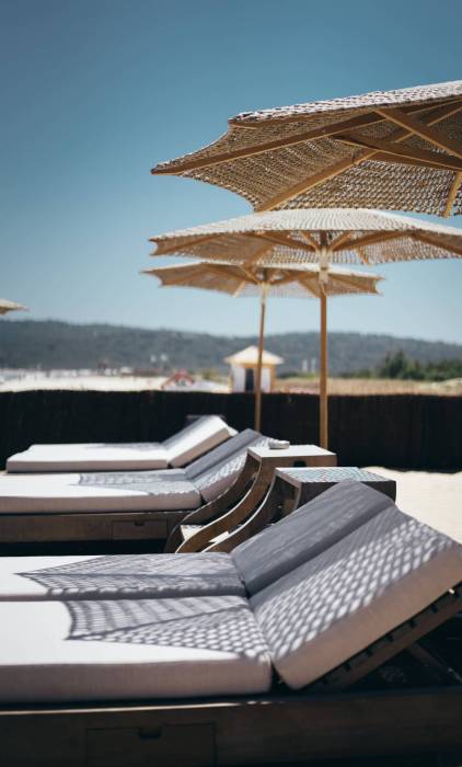 selective-vertical-shot-white-loungers-parasols-by-beach (1)